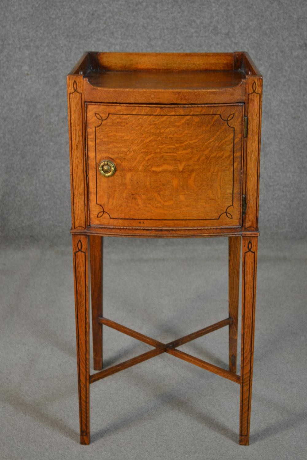 A George III style oak and inlaid bedside cabinet, the gallery top with handles, over a cupboard