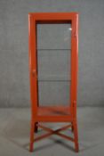 An Ikea orange painted metal display cabinet, with a single glazed door, glazed sides and back,