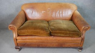A circa 1930s tan leather club sofa, with scrolling arms, and brown velour upholstered seat