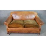 A circa 1930s tan leather club sofa, with scrolling arms, and brown velour upholstered seat