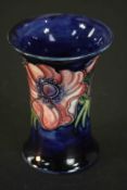 A Moorcroft vase, anemone pattern on dark blue ground, stamped Moorcroft, made in England. H.11