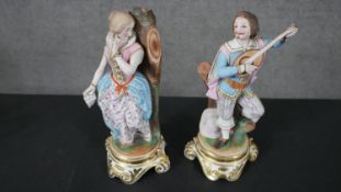 Two hand painted porcelain figures on scrolling design stands, one of a gentleman playing a lute and