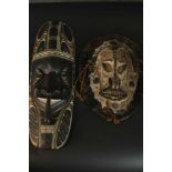 One ancestral mask from Papa New Guinea along with a carved early 20th century African tribal mask.