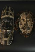 One ancestral mask from Papa New Guinea along with a carved early 20th century African tribal mask.