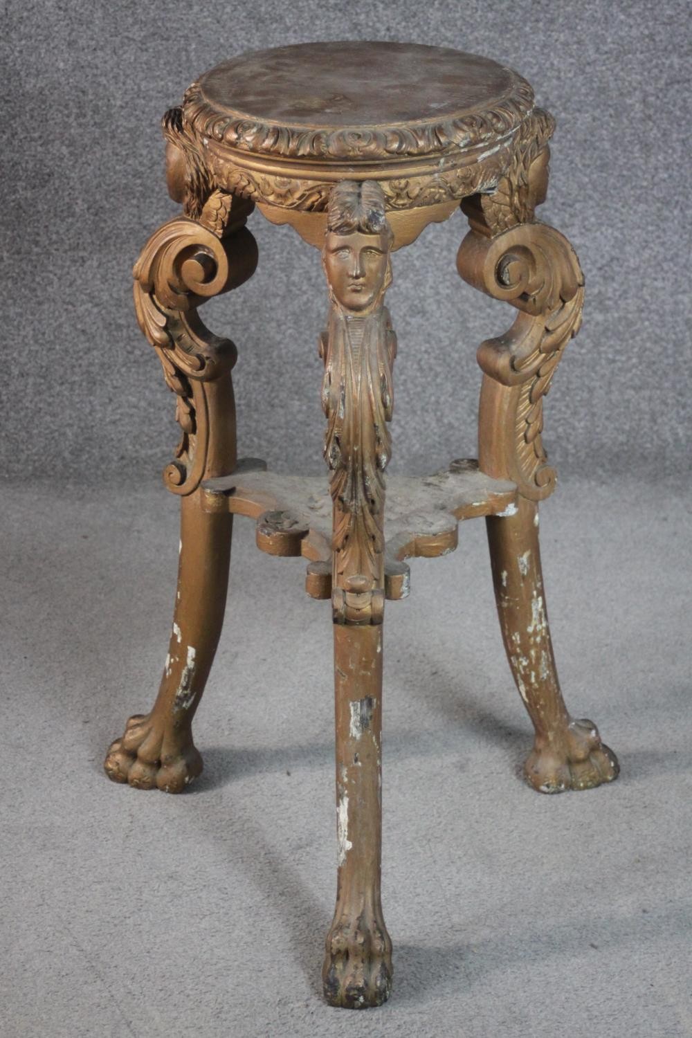 A late 19th century Italian carved wood jardiniere stand, with a circular top, on three ornately