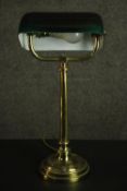 An early 20th century banker's brass desk lamp, with an adjustable green glass shade, on a