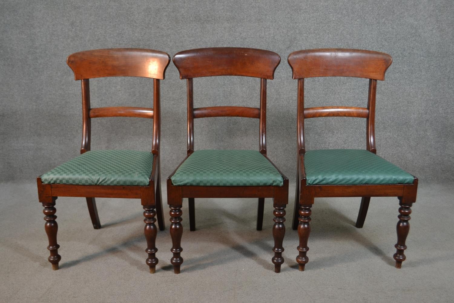 A set of three Victorian mahogany bar back dining chairs, the drop in seat upholstered in green