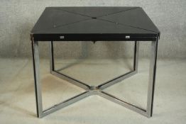 A modernist envelope extending dining table, with a black stained ash extending top, on chromed legs