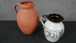Two C H Branham Barum art pottery jugs, one terracotta with clear glaze inside ad one with a