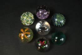 A collection of seven art glass paperweights, including a Caithness black 'Flower in the Rain'