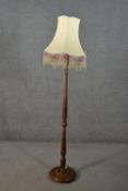 A circa 1920s fruitwood standard lamp, with a turned stem and a circular base, the cream shade