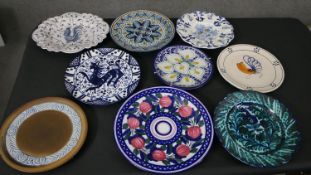 A collection of nine hand painted Majolica pottery chargers, each with a different design and signed