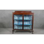 An early 20th century bow front mahogany display cabinet, the gallery back and top both with