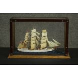 A scratch built model ship, on a scenic base, in a glazed display case. H.29 W.43 D.16cm.