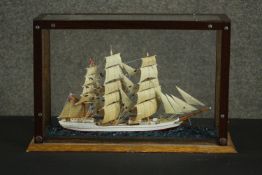 A scratch built model ship, on a scenic base, in a glazed display case. H.29 W.43 D.16cm.