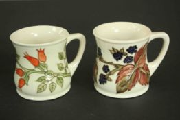 Two boxed Moorcroft pottery mugs. One 'Rosehip' pattern mug, designed by Sally Tuffin for Liberty