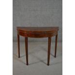 A George III mahogany demi-lune folding card table, with a crossbanded top, the interior lined