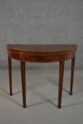 A George III mahogany demi-lune folding card table, with a crossbanded top, the interior lined