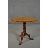 A 19th century mahogany tripod table, with an oval tilt top, on a turned stem, with tripod legs. H.