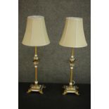 A pair of parcel gilt and white painted table lamps, with leaf detail, on four acanthus leaf feet,