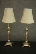 A pair of parcel gilt and white painted table lamps, with leaf detail, on four acanthus leaf feet,