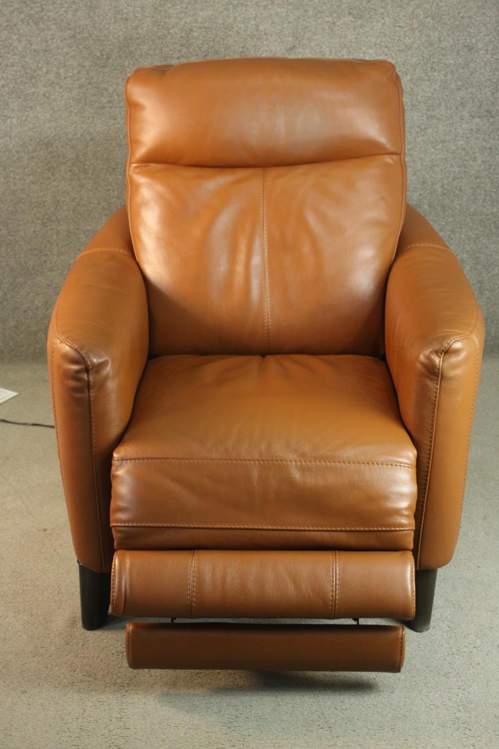 A contemporary tan leather electric reclining armchair, possibly Natuzzi, with instructions. In good