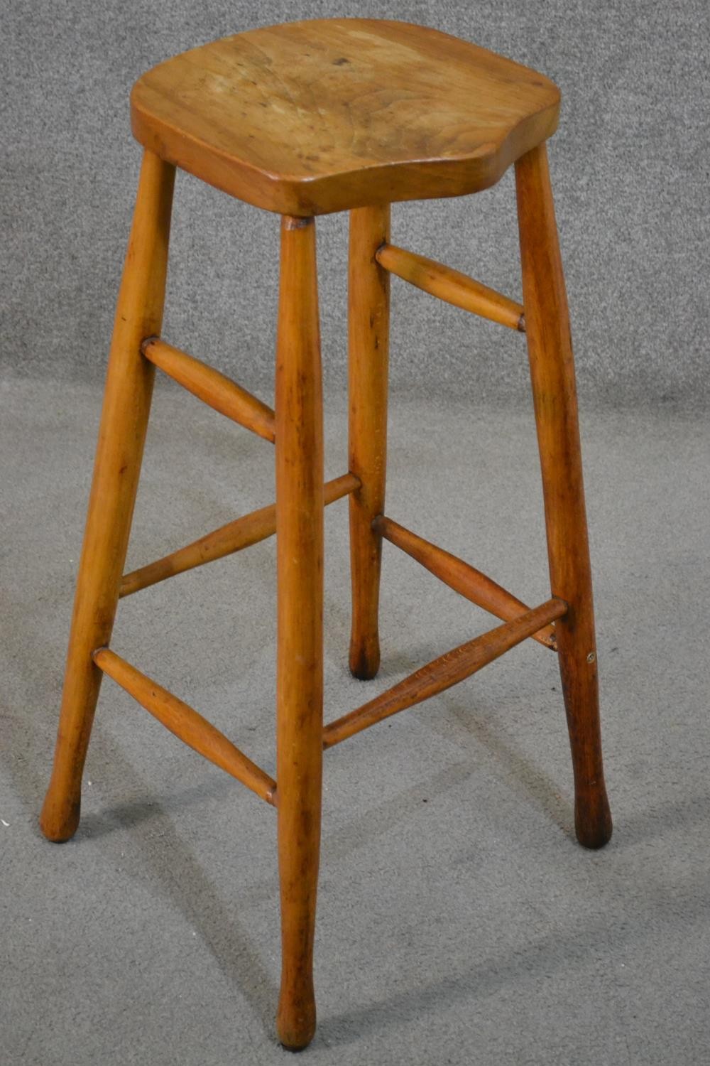 A late 19th/early 20th century bar stool, with a shaped elm seat, the legs joined by stretchers. H. - Image 2 of 5
