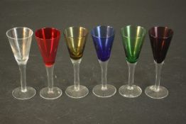 A set of six multi coloured glass wine glasses with clear stems. H.15 Dia.5cm.