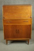 A circa 1960s teak bureau, the fall front opening to reveal a fitted interior, over a single drawer,