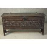 A 17th century oak coffer, the hinged lid with large iron hinges, the front panel ornately carved