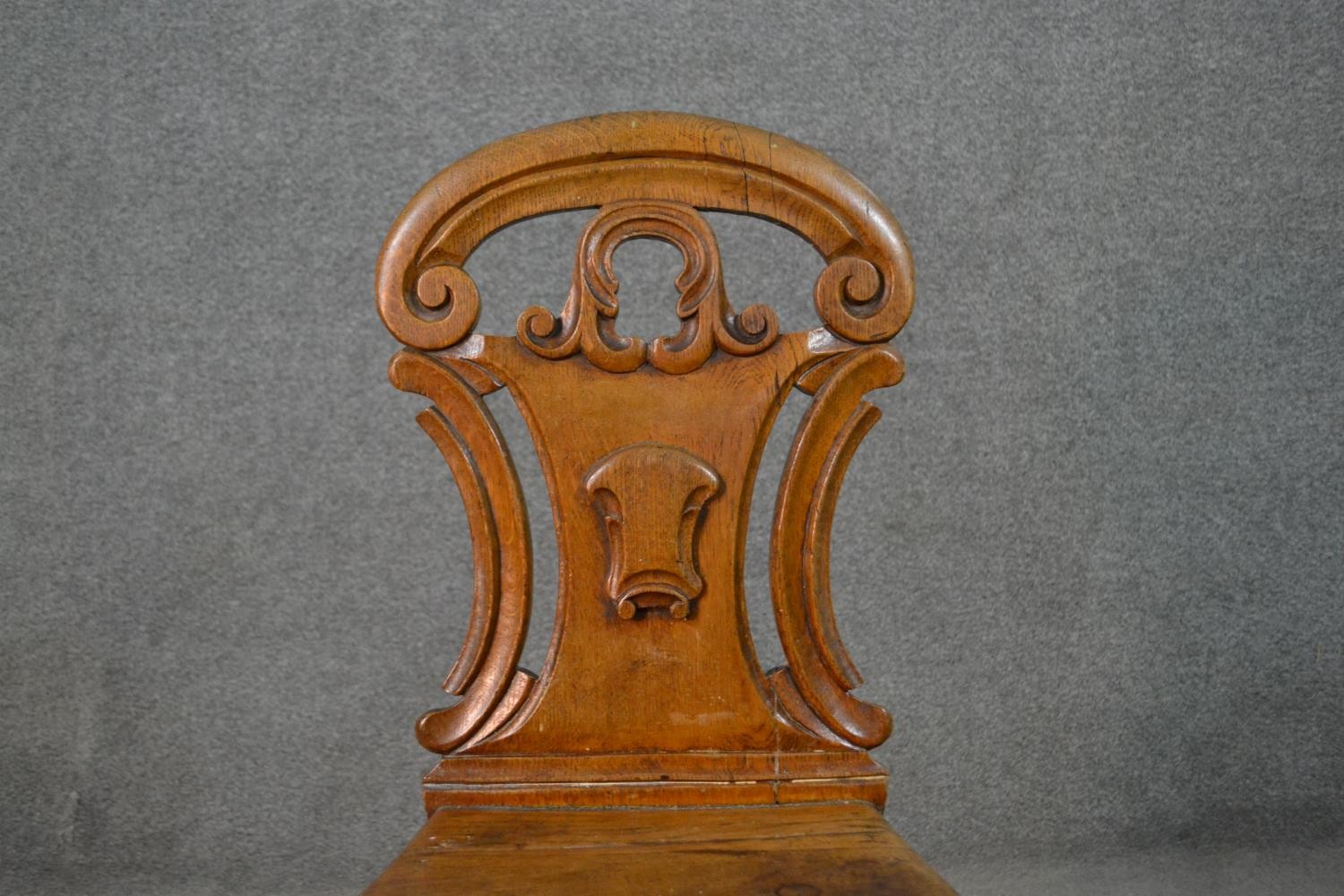 A Victorian oak hall chair, with a carved and pierced scrolling back, on turned legs. - Image 2 of 4