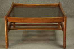 A circa 1960s G-Plan teak coffee table, of square form, with a smoked glass top over a slatted