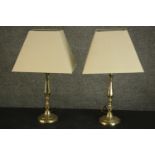 A pair of brass table lamps, with baluster stems and circular bases, with ivory coloured shades. H.