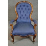 A Victorian walnut spoon back open armchair, upholstered in striped blue fabric, to the arms, seat