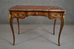 A Louis XV style bureau plat, with a tooled brown leather writing surface, over three short drawers,