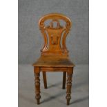 A Victorian oak hall chair, with a carved and pierced scrolling back, on turned legs.