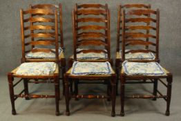 A set of six country oak ladder back dining chairs, with rush seats, on turned legs joined by turned