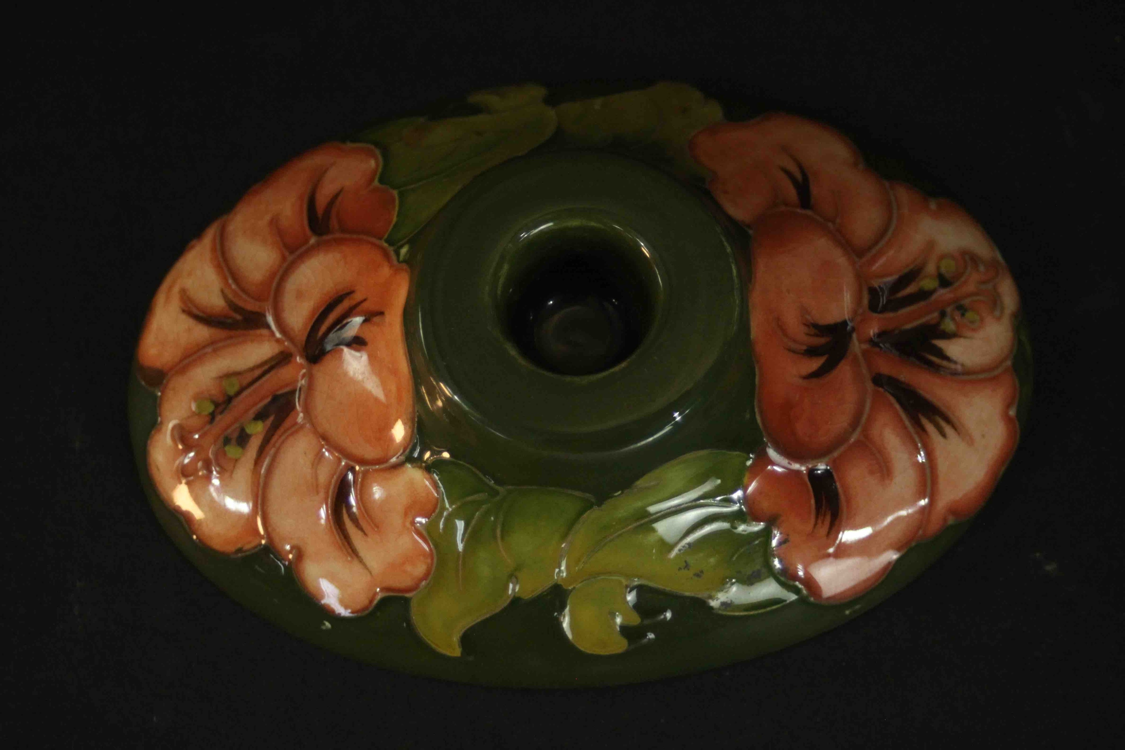 A Moorcroft hibiscus pattern candle holder with peach coloured flowers on a green ground,