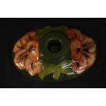 A Moorcroft hibiscus pattern candle holder with peach coloured flowers on a green ground,