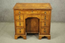 An 18th century style walnut kneehole desk, with a quarter veneered and crossbanded top over a