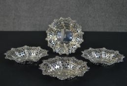 A set of four Victorian pierced repousse design silver dishes with engraved coat of arms to the