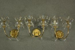 A set of three contemporary gilt brass and Spectra Swarovski crystal two branch wall lights designed
