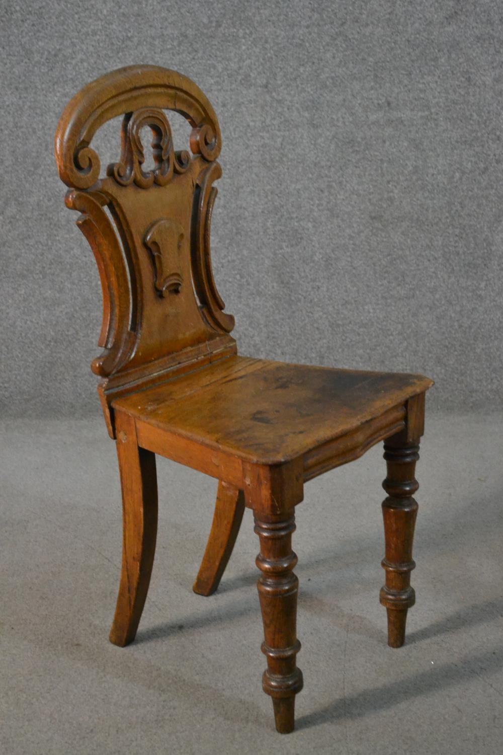A Victorian oak hall chair, with a carved and pierced scrolling back, on turned legs. - Image 4 of 4