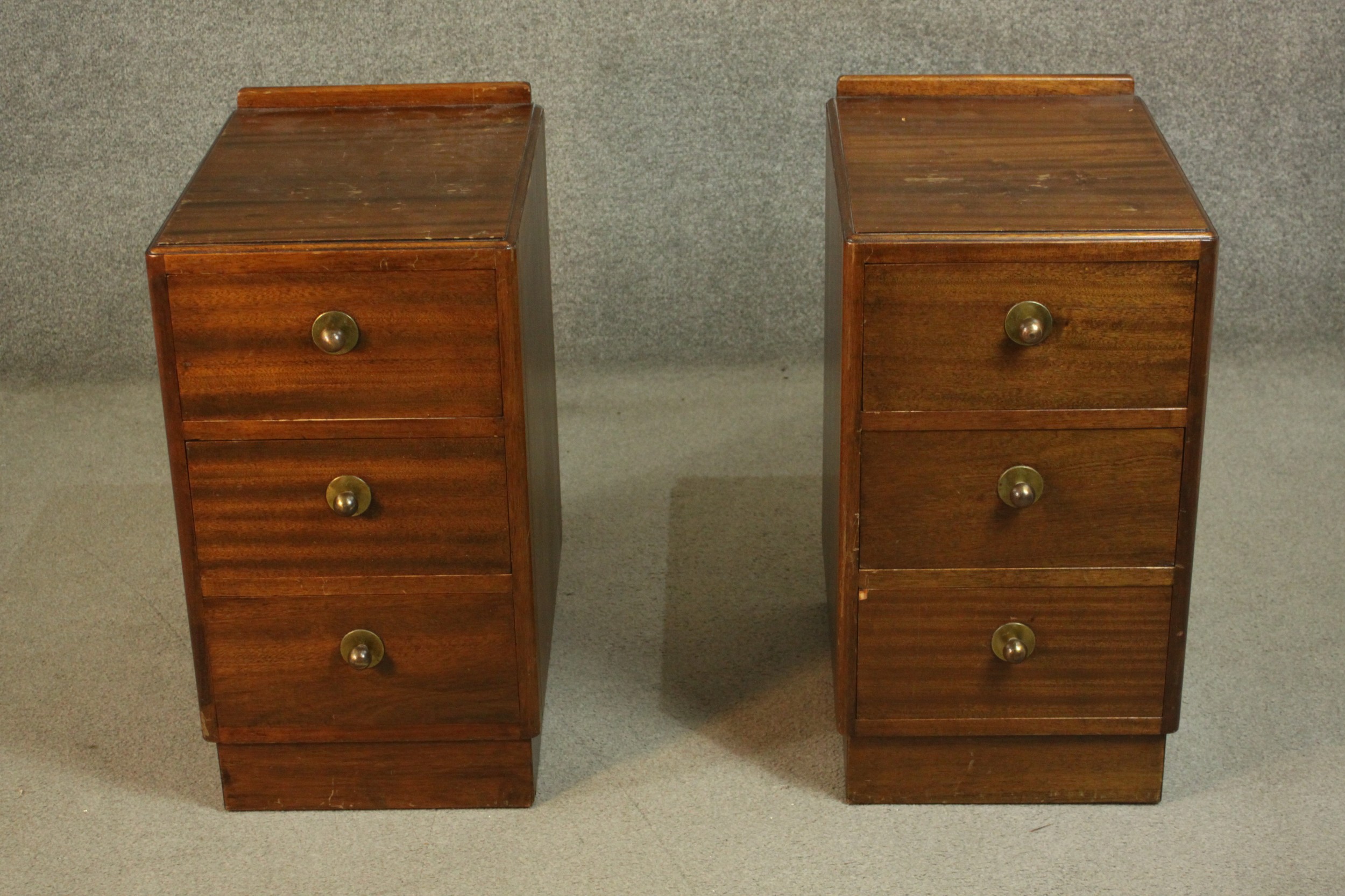 A pair of mid 20th century bedside chests, with a gallery back over three long drawers, on a
