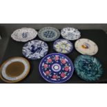 A collection of nine hand painted Majolica pottery chargers, each with a different design and signed