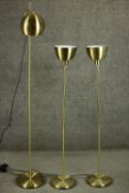 A set of three contemporary brass floor standing lamps, including an adjustable reading lamp and a