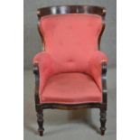A William IV mahogany armchair, with a curved back, upholstered in a patterned pink fabric, buttoned