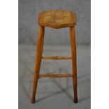 A late 19th/early 20th century bar stool, with a shaped elm seat, the legs joined by stretchers. H.
