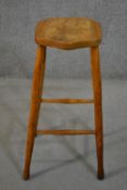 A late 19th/early 20th century bar stool, with a shaped elm seat, the legs joined by stretchers. H.