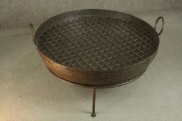 A contemporary steel fire pit, with two handles and a grille, on an iron stand. H.50 Dia.80cm.